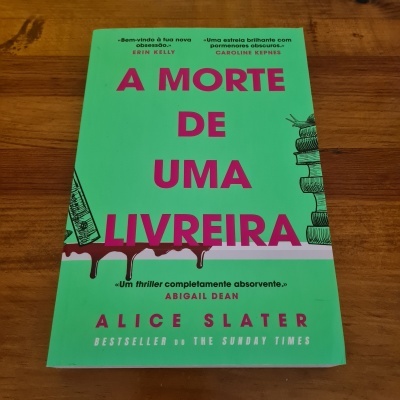 Capa do livro 'A Morte de Uma Livreira' com texto e ilustrações sobre superfície de madeira