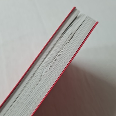 Livro visto do topo com capa vermelha e páginas amassadas