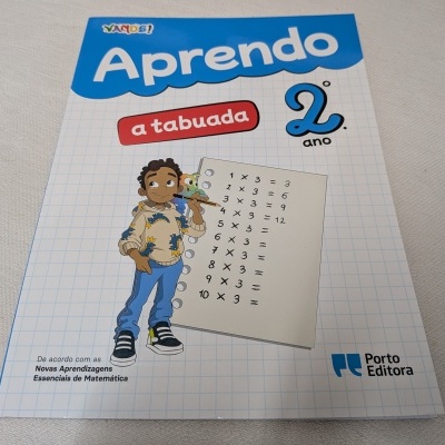 Capa de livro 'Aprendo a tabuada 2.º ano' com desenho de menino e tabuadas