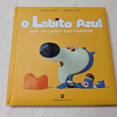 Livro infantil o Lobito Azul quer um penico com rodinhas! capa dura amarela com ilustração de lobo azul