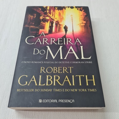 Capa do livro A Carreira do Mal de Robert Galbraith com imagem urbana alaranjada