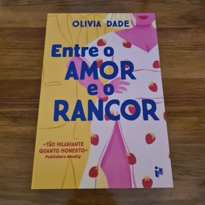 Livro colorido 'Entre o AMOR e o RANCOR' com ilustração de morangos sobre madeira