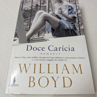 Livro 'Doce Carícia' de William Boyd com fotografia de mulher em vestido azul na capa