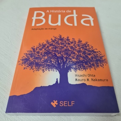 Capa de livro laranja e roxa com árvore e texto A História de Buda