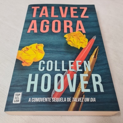 Capa de livro 'Talvez Agora' de Colleen Hoover com canetas e bolas de papel amarelo