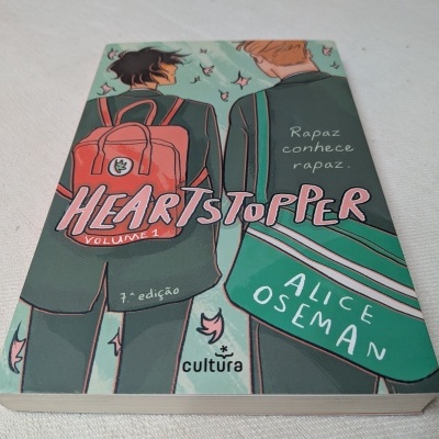 Capa de livro Heartstopper Volume 1 com ilustração de duas pessoas em uniformes escolares e texto visível