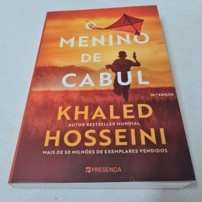Capa do livro Menino de Cabul de Khaled Hosseini com fundo laranja e silhueta de menino a correr