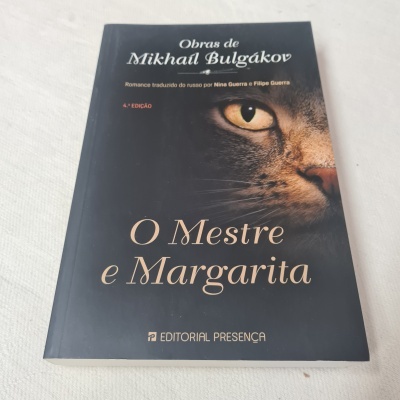 Capa preta do livro 'O Mestre e Margarita' com rosto de gato e texto em branco e bege