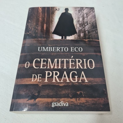 Capa do livro O Cemitério de Praga de Umberto Eco com figura a subir escadas e dois cães