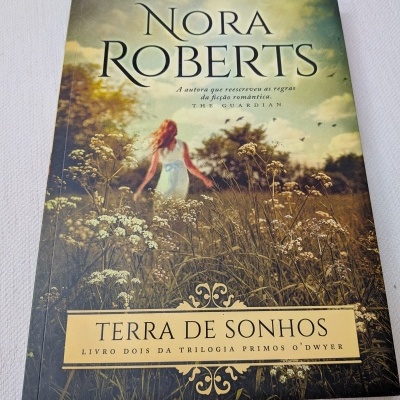 Capa de livro com mulher num campo e texto do título e autor