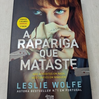 Capa do livro A Rapariga que Mataste de Leslie Wolfe com imagem de rapariga segurando papel