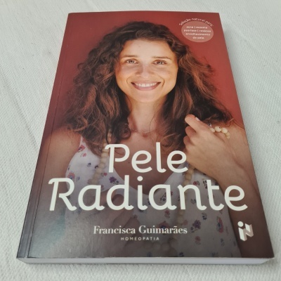 Capa de livro 'Pele Radiante' com foto de mulher sorridente e cabelo encaracolado.