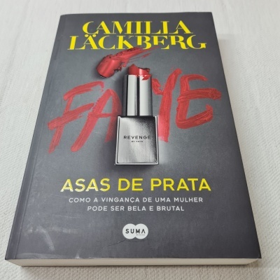 Capa do livro 'Faye Asas de Prata' com imagem de batom vermelho e texto em amarelo e vermelho sobre fundo cinza.