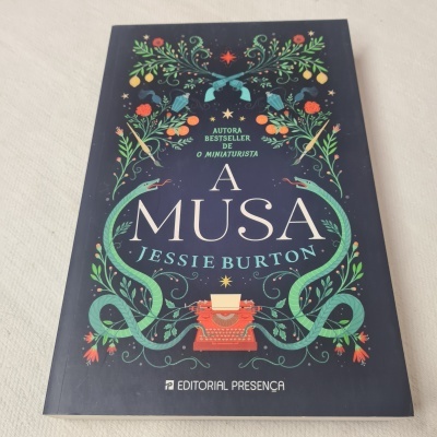 Livro A Musa de Jessie Burton com capa azul escura e ilustrações coloridas