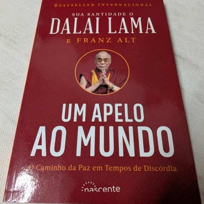 Capa de livro vermelho com título UM APELO AO MUNDO e imagem do Dalai Lama