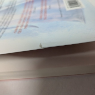 Livro ou revista com canto vincado e rasgado ligeiramente visível