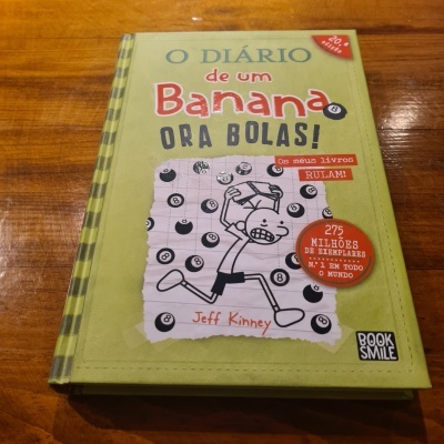 Livro 'O Diário de um Banana: Ora Bolas!' com capa verde, ilustração a preto e branco e textos em vermelho e preto