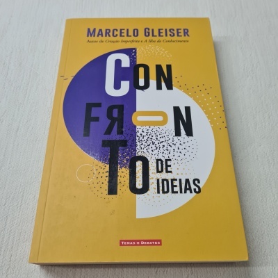 Livro com capa amarela e título 'Confronto de Ideias' de Marcelo Gleiser