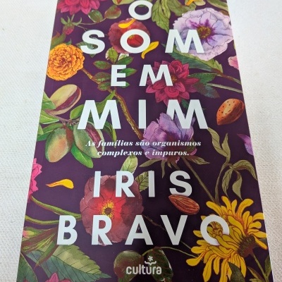 Livro com capa floral roxa com texto O SOM EM MIM IRIS BRAVO e subtítulo em branco.