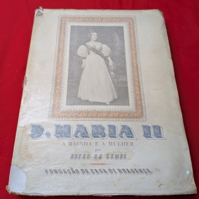 Livro antigo com imagem e texto na capa sobre fundo vermelho