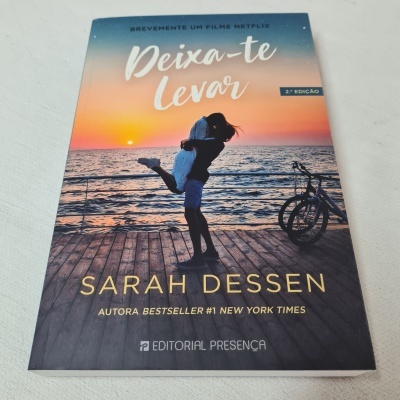 Capa de livro 'Deixa-te Levar' com casal na praia ao pôr do sol e texto informativo