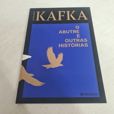 Livro 'O ABUTRE E OUTRAS HISTÓRIAS' de Franz Kafka com capa azul e preta e ilustração de abutres dourados
