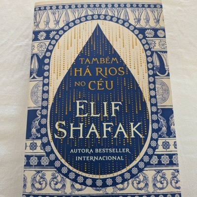 Capa de livro azul e bege com detalhes florais, título e autor em relevo
