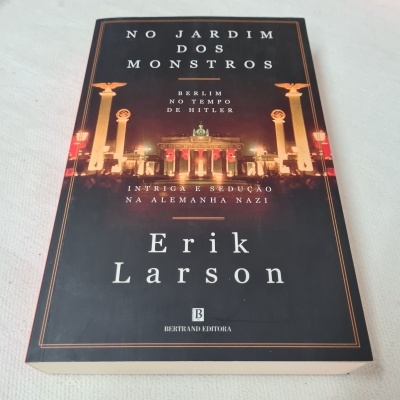 Livro 'No Jardim dos Monstros' de Erik Larson com imagem noturna da Porta de Brandemburgo em Berlim.