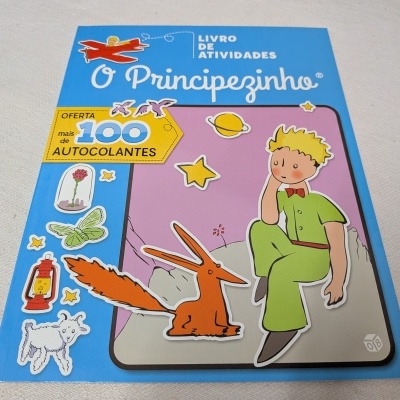 Livro de atividades O Principezinho com vários autocolantes coloridos à esquerda