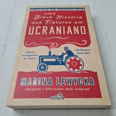 Capa do livro 'Uma Breve História dos Tratores em Ucraniano' com trator azul e detalhes em vermelho