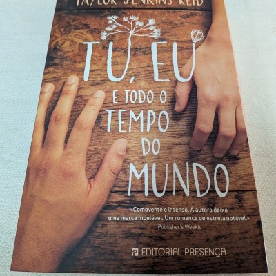 Capa de livro com duas mãos sobre fundo de madeira e título em branco