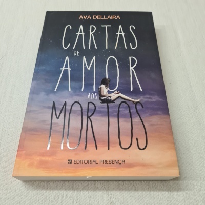 Livro 'Cartas de Amor aos Mortos' com capa ilustrada mostrando céu ao pôr do sol e rapariga sentada