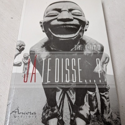 Capa de livro com escultura sorridente em preto e branco, título JÁ TE DISSE...? e autor Daniel Carvalho.