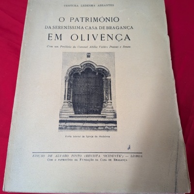 Capa de livro antigo com texto e foto de porta de igreja em fundo vermelho.