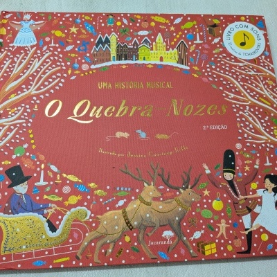 Capa do livro infantil vermelho O Quebra-Nozes com ilustrações e selo musical.