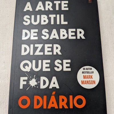 Capa de livro preta com títulos brancos e laranja e selo branco com texto