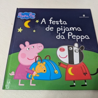Livro infantil A festa de pijama da Peppa com personagens de desenho animado Peppa Pig e zebra na capa