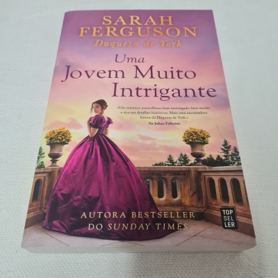Capa do livro 'Uma Jovem Muito Intrigante' com mulher de vestido roxo e texto em dourado e preto
