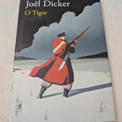 Capa de livro com homem armado em paisagem nevada e o título Joël Dicker O Tigre.