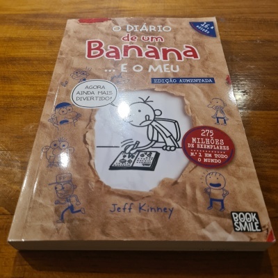 Capa do livro O Diário de um Banana - E o Meu de Jeff Kinney sobre mesa de madeira