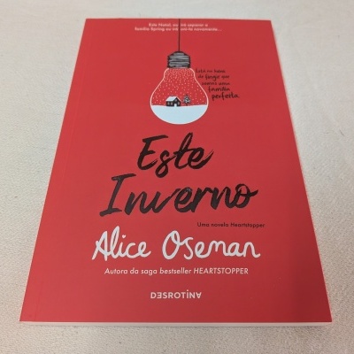Capa vermelha do livro 'Este Inverno' de Alice Oseman com lâmpada desenhada