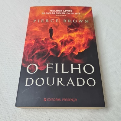 Livro 'O Filho Dourado' com capa em chamas vermelhas e laranja sobre fundo branco
