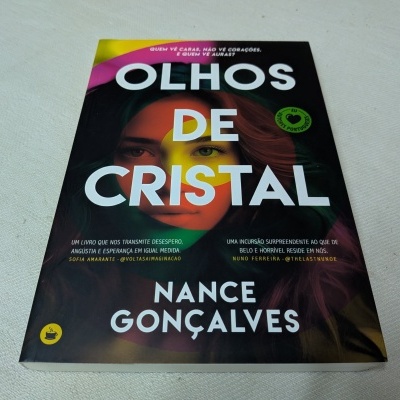 Capa do livro 'Olhos de Cristal' com rosto colorido e texto em branco