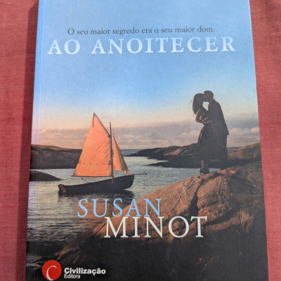 Capa do livro Ao Anoitecer com casal e barco ao pôr do sol