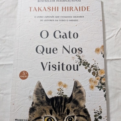 Livro 'O Gato Que Nos Visitou' com ilustração de gato e flores na capa