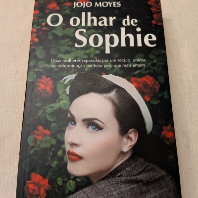 Capa do livro O olhar de Sophie de Jojo Moyes com imagem de mulher vintage e flores vermelhas ao fundo