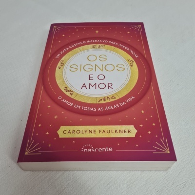 Livro 'Os Signos e o Amor' com capa vermelha e detalhes dourados