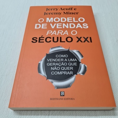 Livro laranja 'O MODELO DE VENDAS PARA O SÉCULO XXI' de Jerry Acuff e Jeremy Miner sobre fundo branco