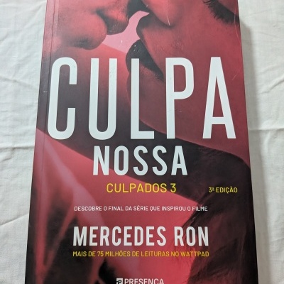 Livro 'CULPA NOSSA' de Mercedes Ron com capa vermelha e preta mostrando casal perto um do outro.