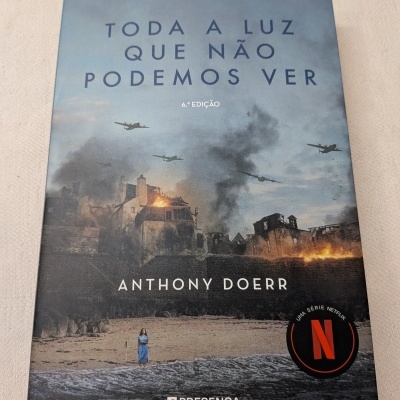 Capa do livro Toda a luz que não podemos ver com cenário de guerra e texto informativo.